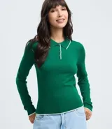 Blusa de punto de manga larga con cuello polo y cierre frontal parcial. Presenta un diseño ajustado al cuerpo en color blanco con detalles de ribetes en contraste en el cuello, puños y ruedo.