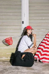 Bolso deportivo tipo duffel bag de nylon color verde oliva, con asas de mano y correa ajustable para llevar al hombro.