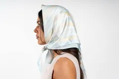 Pañuelo cuadrado de seda con estampado de rayas diagonales en tonos celestes y amarillos, y detalle de rama de olivo.