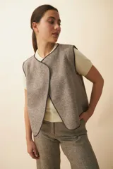 Chaleco marrón con textura, corte holgado, cuello en V y terminaciones con ribete en contraste. Diseño reversible.