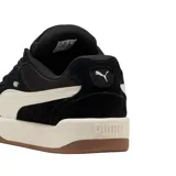 Championes Puma de estilo skate, color negro con la franja lateral característica en blanco. Presentan una suela de plataforma blanca con base de goma color caramelo.