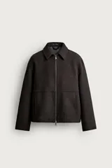 Cazadora regular fit de color marrón oscuro, confeccionada en tejido con mezcla de lana. Cuenta con cuello solapa, manga larga, bolsillos de vivo en la cadera y cierre frontal con cremallera de doble dirección.