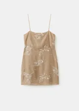 Vestido corto recto en color beige, con tirantes finos y escote recto. Presenta un delicado diseño bordado floral en hilo metalizado y cuenta con un bolsillo frontal superpuesto a la altura de la cadera.