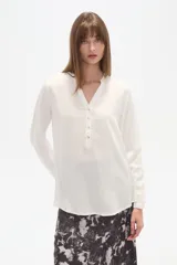 Blusa de viscosa color blanco, con cuello mao y cierre frontal parcial con botones. Presenta un diseño de corte al cuerpo y mangas largas.