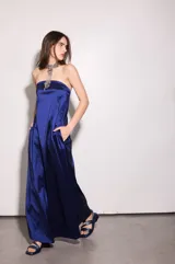 Vestido largo azul con escote strapless, corte suelto y fluido, confeccionado en tafeta con efecto tornasolado, y bolsillos ocultos en los laterales.