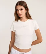 Remera de algodón color blanco tiza, de corte ajustado al cuerpo, cuello redondo y manga corta. Presenta la palabra "GNARLY" estampada en el centro del pecho con apliques de strass plateados.