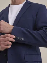 Blazer formal color negro, confeccionado en tela texturada, con solapas clásicas, cierre de dos botones frontales y bolsillos con solapa.