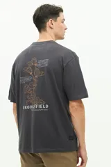 Remera de manga corta color blanco con diseño estampado en la espalda que incluye motivos florales y texto. Presenta un corte regular y cuello redondo.