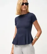 Blusa de corte peplum confeccionada en tejido Punto Roma, con escote redondo, mangas cortas y recortes estructurados que definen la silueta.