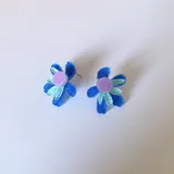 Aros tipo botón con forma de flor de pétalos turquesa y centro rosa y naranja.