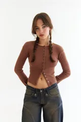 Top de manga larga color amarillo, confeccionado en tejido acanalado con cierre frontal de botones a presión metálicos. Presenta detalles de botones en los puños y un corte ajustado al cuerpo.