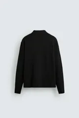 Polo de punto de manga larga con cuello solapa y cierre frontal de botones. Presenta un diseño de corte regular con aberturas laterales en el bajo.