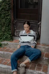 Sweater tipo polo de punto con diseño color block en tonos gris, blanco y negro. Presenta cuello camisero en contraste, cierre frontal con botones y mangas largas.