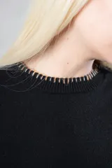 Sweater de punto color rosa claro, con cuello redondo a la base, mangas largas y puños acanalados. Presenta detalles de terminación a mano en contraste en el cuello, puños y ruedo.