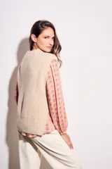 Chaleco de punto color beige con cuello alto y sisas amplias.