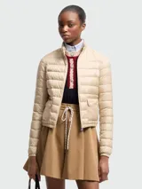 Campera corta tipo puffer de Moncler, confeccionada en nylon ligero con diseño acolchado horizontal. Presenta cuello alto, cierre frontal con cremallera, bolsillos laterales con solapa y ajuste elástico en los puños.