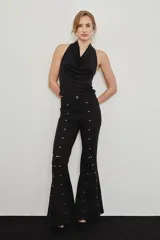 Jean de corte flare color negro, con detalles de tachas plateadas a lo largo de las costuras delanteras y godets en la parte baja para generar mayor vuelo.