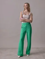 Pantalón naranja de crepe elastizado, corte recto, con bolsillos delanteros y apliques de botones metálicos.