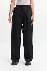 Pantalón negro de corte wide leg, confeccionado en tela satinada. Tiene cintura elastizada con lazo ajustable.