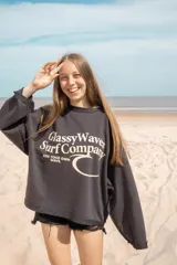 Buzo negro de corte amplio con estampado frontal de la marca 'Classy Waves' en color blanco. Es de mangas largas y cuello redondo. Es reversible y se puede usar de ambos lados.