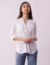 Blusa color beige de lino, marca Dash. Cuello a la base, escote en V y abertura con botones. Delantera con bolsillos. Largo de manga regulable con presilla y botón.