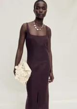 Vestido midi color borgoña de lino, con breteles anchos, escote cuadrado, corte recto, abertura frontal en el ruedo y detalle de costuras verticales.