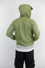 Campera verde oliva de nylon anti-lluvia, con capucha, cierre frontal y puños y cintura en tejido de punto gris. Presenta un logo bordado en el pecho.