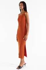 Vestido midi sin mangas de punto jersey con hilo Lurex en tono naranja cobrizo y destellos brillantes. Presenta escote bote y aberturas laterales.