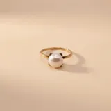 Anillo de oro 9k con perla de cultivo central engastada en cuatro garras.