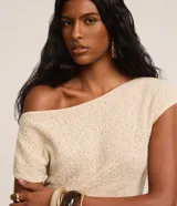 Blusa de punto color crema, con escote asimétrico, mangas cortas, textura y fruncido lateral.