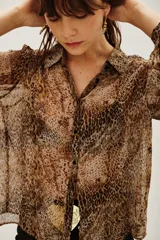 Camisa de manga larga con cuello camisero y cierre frontal de botones, confeccionada en tejido fluido con estampado animal print de leopardo.