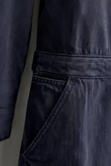 Mono oversize fit de algodón con estructura espiga en color azul marino, con cuello solapa en contraste de color tostado, manga larga, bolsillos de plastrón en el pecho con firma bordada, trabillas laterales en la cintura y cierre frontal con cremallera y botonadura oculta.