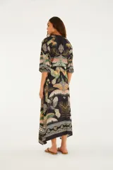 Vestido largo negro con estampado multicolor de inspiración tropical y geométrica, escote en V, mangas tres cuartos amplias y cordón ajustable en la cintura.