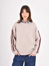 Buzo de tejido de punto en color beige, con cuello redondo, mangas largas y detalle de franjas verticales en color bordó a lo largo de los brazos.