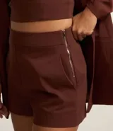 Short lila de tejido bengaline, con bolsillos delanteros y cremallera lateral.