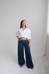 Camisa de corte clásico en color blanco, con cuello camisero, cierre frontal de botones y mangas largas con puños abotonados.