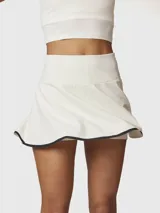 Falda short deportiva color blanco con borde inferior en contraste negro. Presenta un diseño de tiro alto con falda acampanada y short integrado con bolsillo oculto.