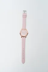 Reloj analógico con correa de cuero sintético color rosado pálido y caja de metal color oro rosado. La esfera es de color rosa pálido con números en relieve en oro rosado.