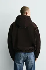 Cazadora de pana de algodón con interior acolchado, diseño relaxed fit, capucha y cierre frontal con cremallera oculta y alamares metálicos. Presenta bolsillos de vivo en la cadera, puños con botón y bajo elástico.