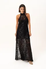 Vestido largo de encaje negro con destellos de lurex, diseño de cuello halter y tajos laterales. Incluye un vestido corto removible como forro interno.