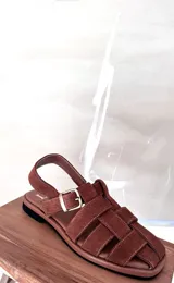 Sandalias de cuero marrón con diseño de tiras entretejidas y hebilla lateral.