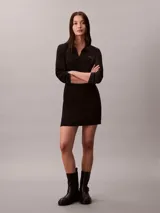 Vestido corto negro de Calvin Klein, de corte slim, confeccionado en algodón acanalado y lycra. Presenta diseño de manga larga, cuello tipo chomba con escote en V y el monograma de la marca bordado en el pecho.