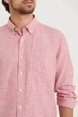 Camisa de manga larga confeccionada en una mezcla de algodón y lino, con cuello abotonado, cierre frontal de botones y un bolsillo en el pecho.