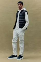 Chaleco acolchado negro con cuello alto, cierre frontal con cremallera y bolsillos laterales con cremallera.