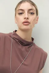 Vestido corto de punto color negro, sin mangas, con cuello cerrado y hombros levemente estructurados. Presenta frunce lateral que realza la figura.