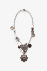 Pack de dos collares de diferente longitud con eslabones metálicos plateados. El primer collar presenta un colgante de corazón labrado con incrustaciones de piedra y cristal. El segundo collar incluye un colgante de medalla labrada con detalles en resina a color.