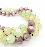 Collar de tres hilos de cuentas redondas de resina en colores lila, verde y amarillo con detalles brillantes.