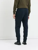 Pantalón jogging de tejido circular con cintura elástica y cordón ajustable. Presenta puños elastizados en el ruedo y bolsillos laterales.