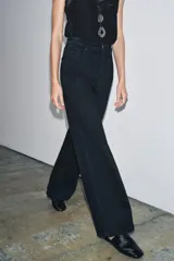 Jeans de tiro alto con corte wide leg y largo completo. Presenta diseño de cinco bolsillos, trabillas en la cintura y cierre frontal con cremallera y botón, con un acabado de efecto lavado.