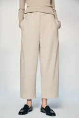 Pantalón de tiro medio con corte tipo ballon, bolsillos delanteros y detalle de pinzas. Cuenta con cierre frontal de cremallera y gancho metálico.